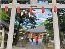 提灯が飾られた鳥居の向こうには神社に向かって歩いている子供連れの家族の姿が見える。