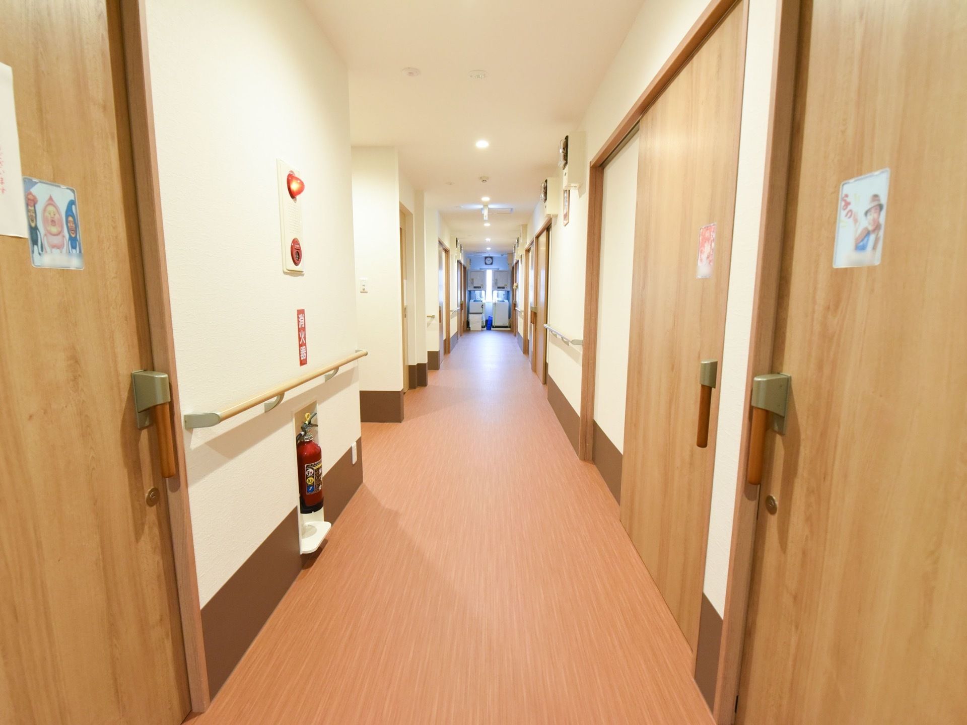 居室が並ぶ廊下は、暖色系の落ち着いた雰囲気である。扉は大きなスライド式になっており、安全に開け閉めすることができる。