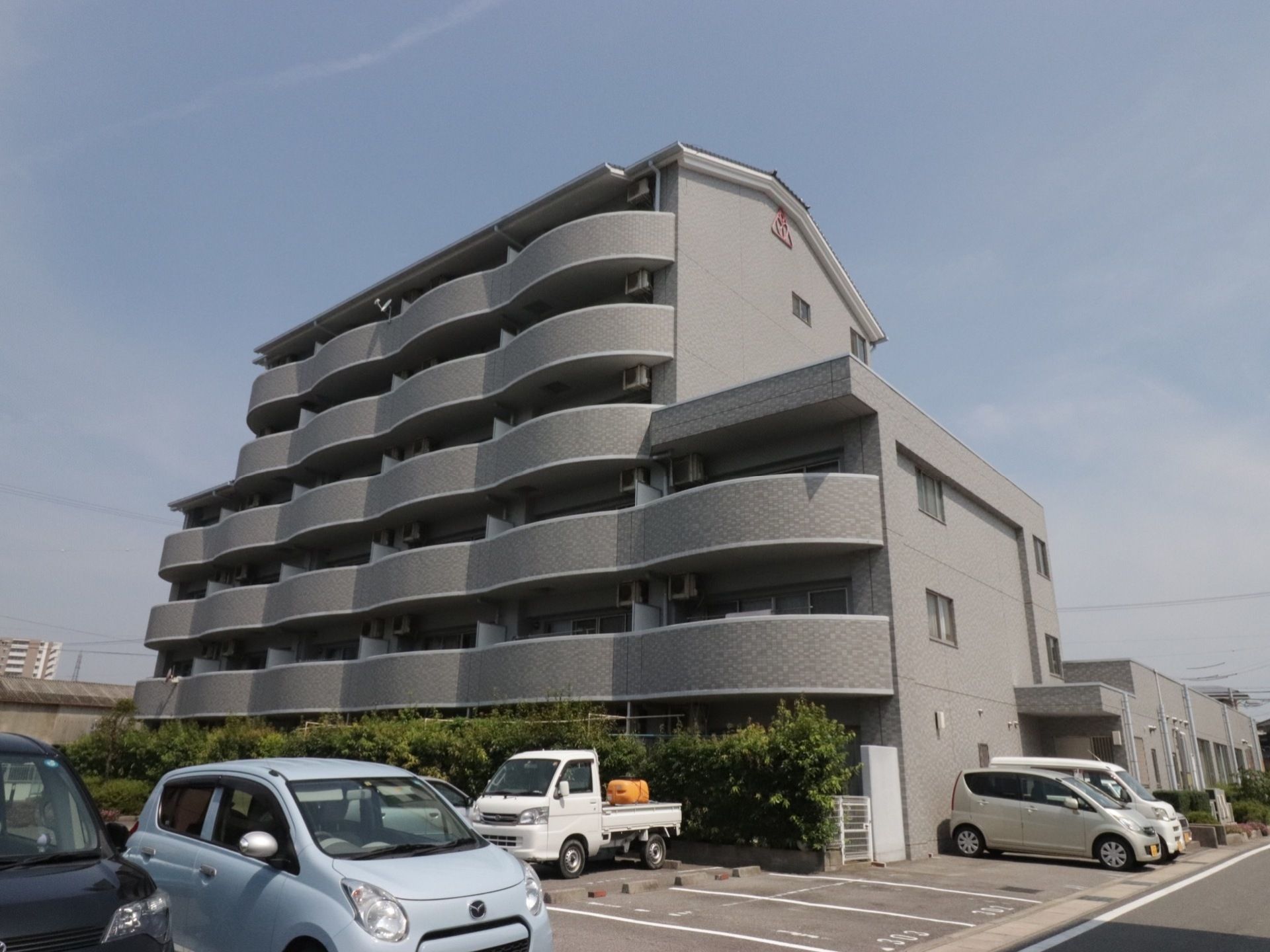 ２階以上にベランダの備わった、６階建てのグレーの外壁の建物である。建物廻りは舗装され、駐車スペースが整備されている。
