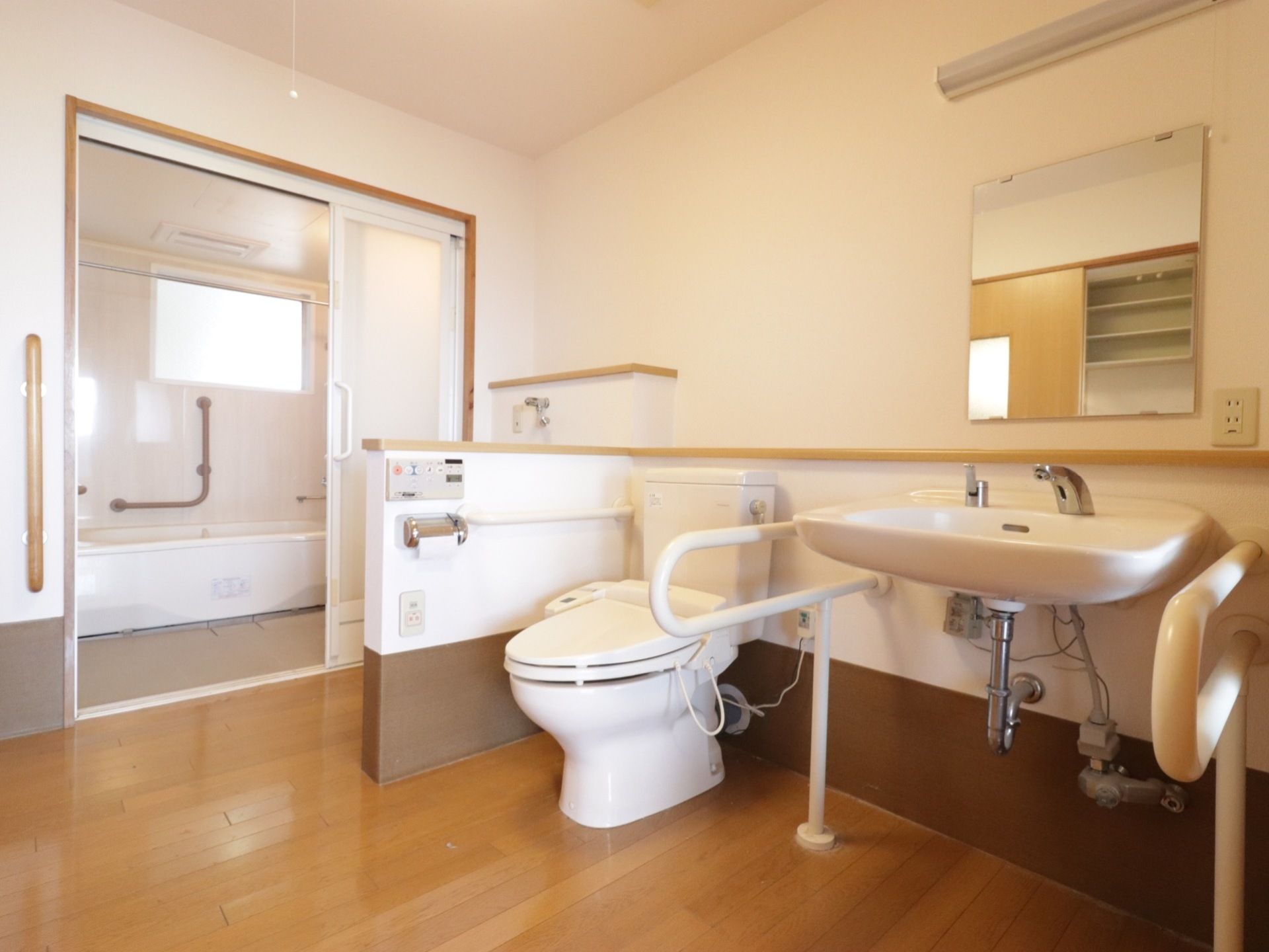 奥に浴室があり、手前のオープンスペースにトイレや洗面台が設置されている。各所に手すりが備わっている。