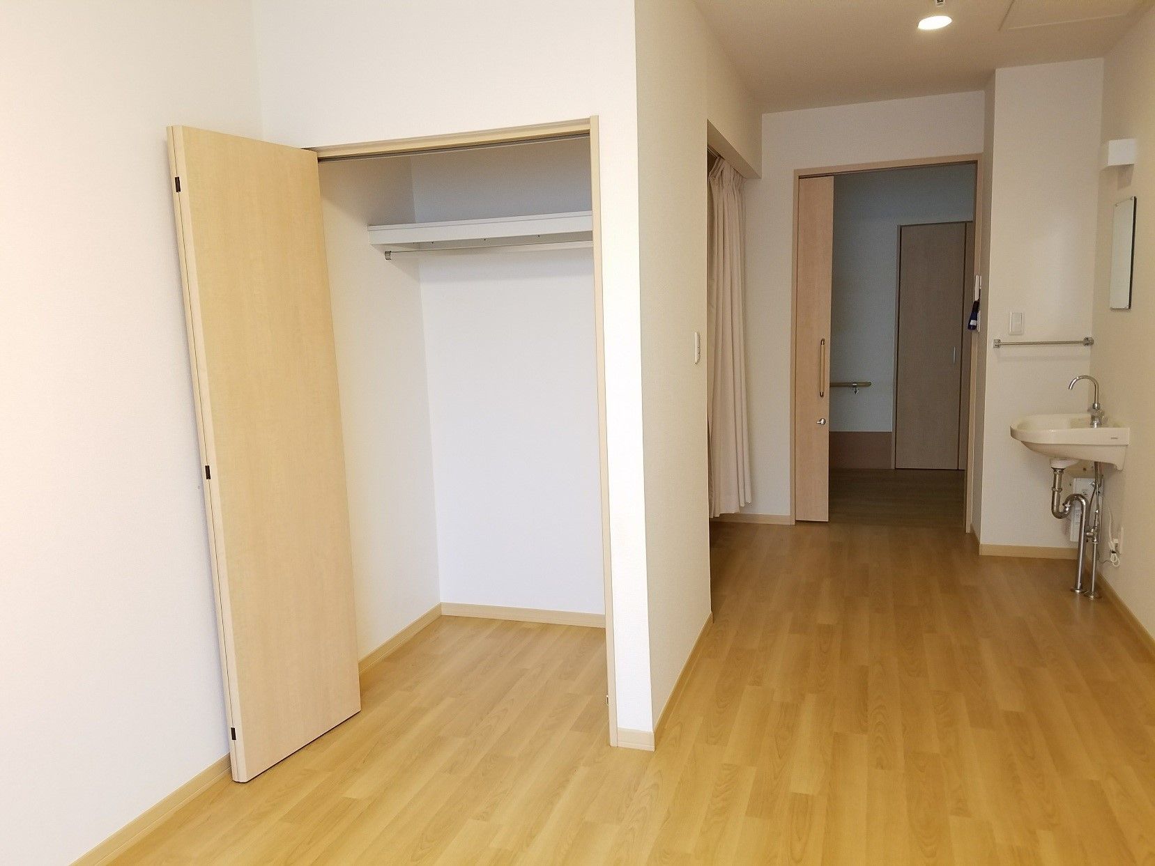 クローゼットタイプの収納がある一人用の部屋。奥に洗面台が写っている