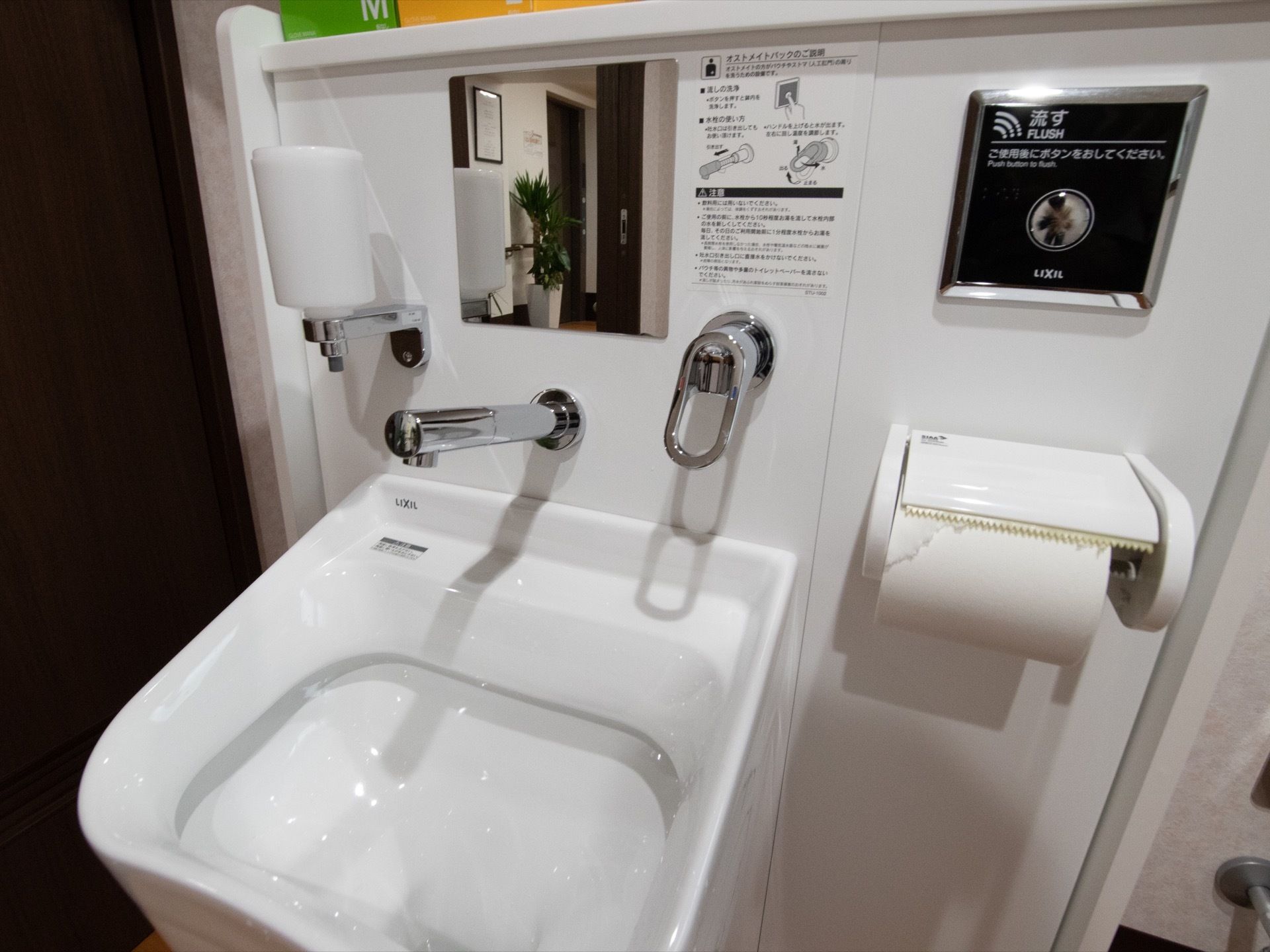 トイレスペースに設けた白を基調とした洗面台である。正面に鏡を設け、その横側に使い方の説明が貼られている。