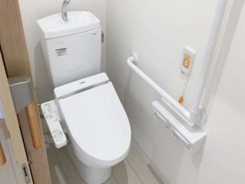 緊急コールと手すりが取り付けてあるトイレ。引き戸のドアが見える