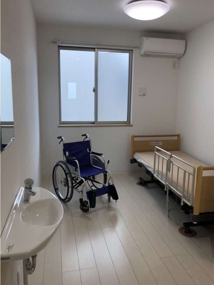 エアコン、車いす、ベッドが写っている個室。窓が取り付けてある