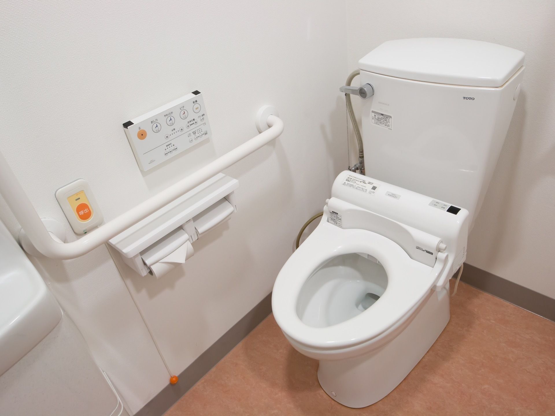 トイレの壁には、立ち居の際に摑まることができる手すりが設置されている。洗浄機能付きの便器で、快適にご利用いただける。