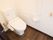 洋式のトイレの個室で、個室内は白色を基調としており清潔感がある。手すりや緊急時呼び出しベルが備わっている。