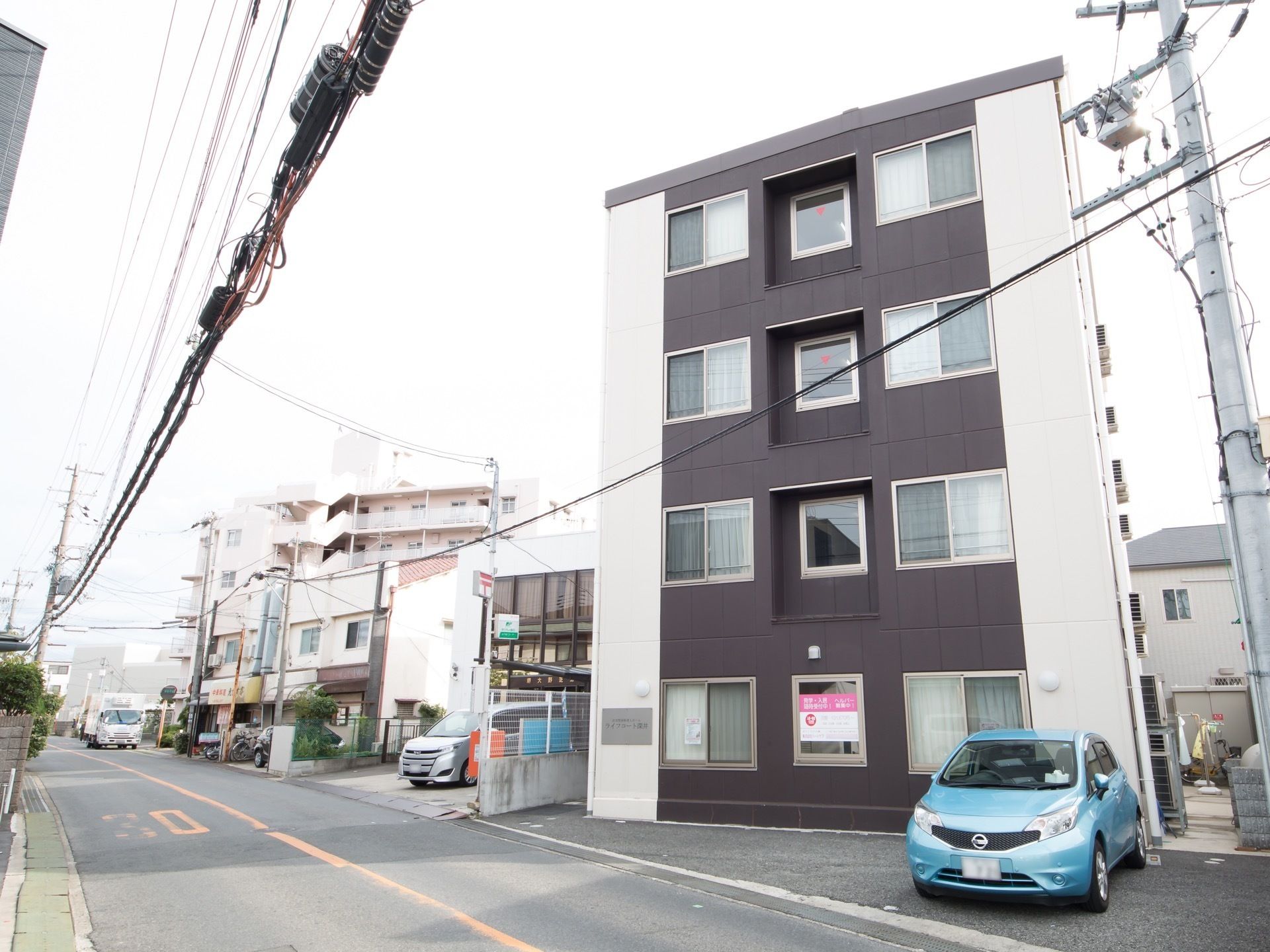 白色とダークグレーを基調とした施設のってものは4階建てで、モダンなデザインの外観である。郵便局が隣接している。