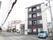 白色とダークグレーを基調とした施設のってものは4階建てで、モダンなデザインの外観である。郵便局が隣接している。