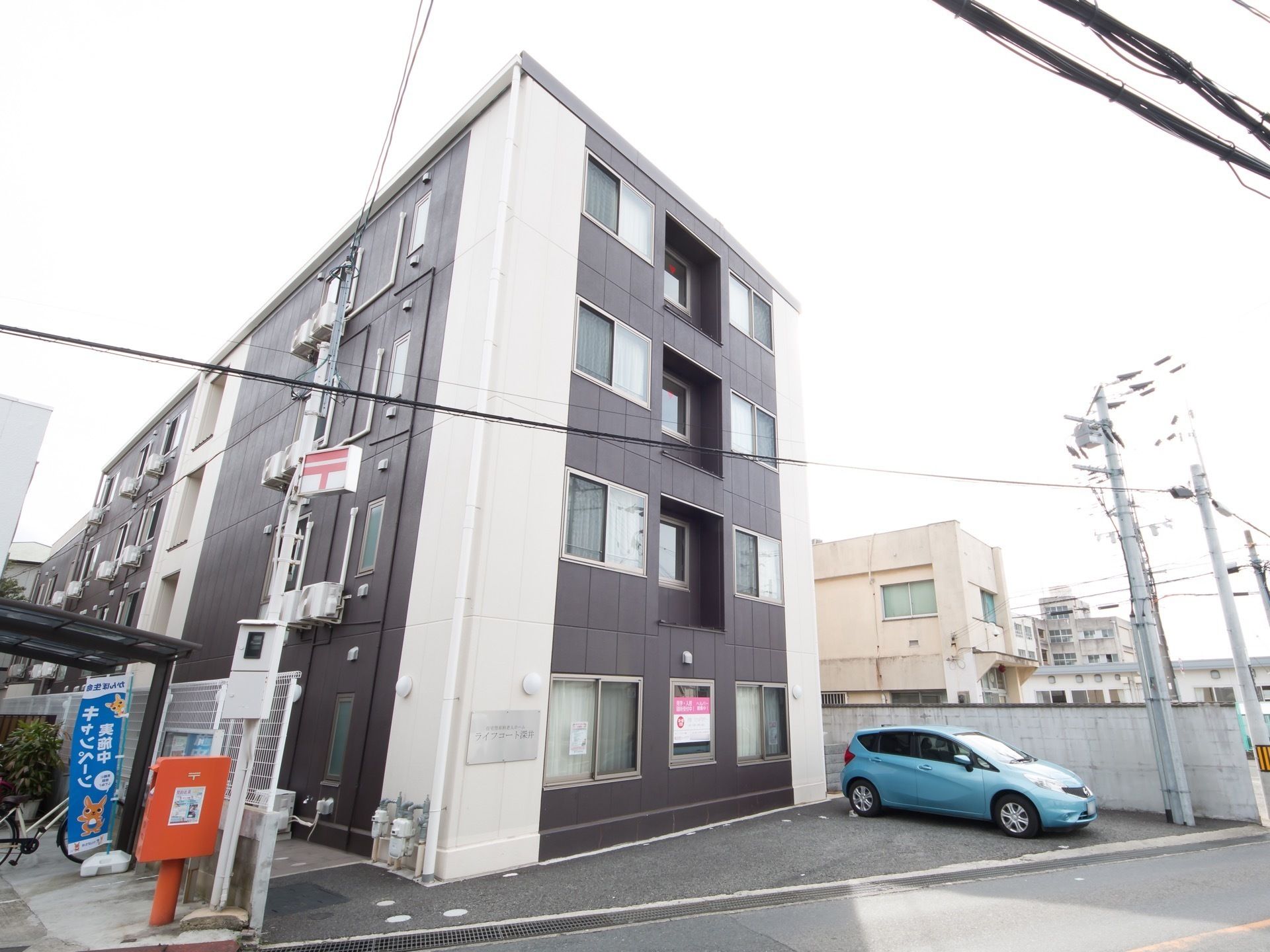 ブラウンの建物は3階建て。白いラインがアクセントとして入っている。