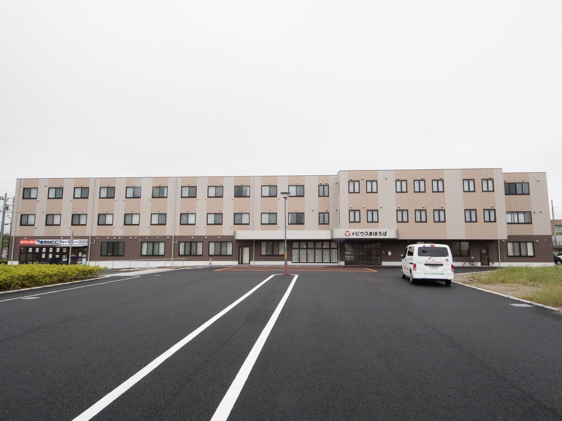 ３階建ての横に長い建物で、玄関の屋根に大きく施設名が書かれている。敷地内の道路はきれいに舗装されている。