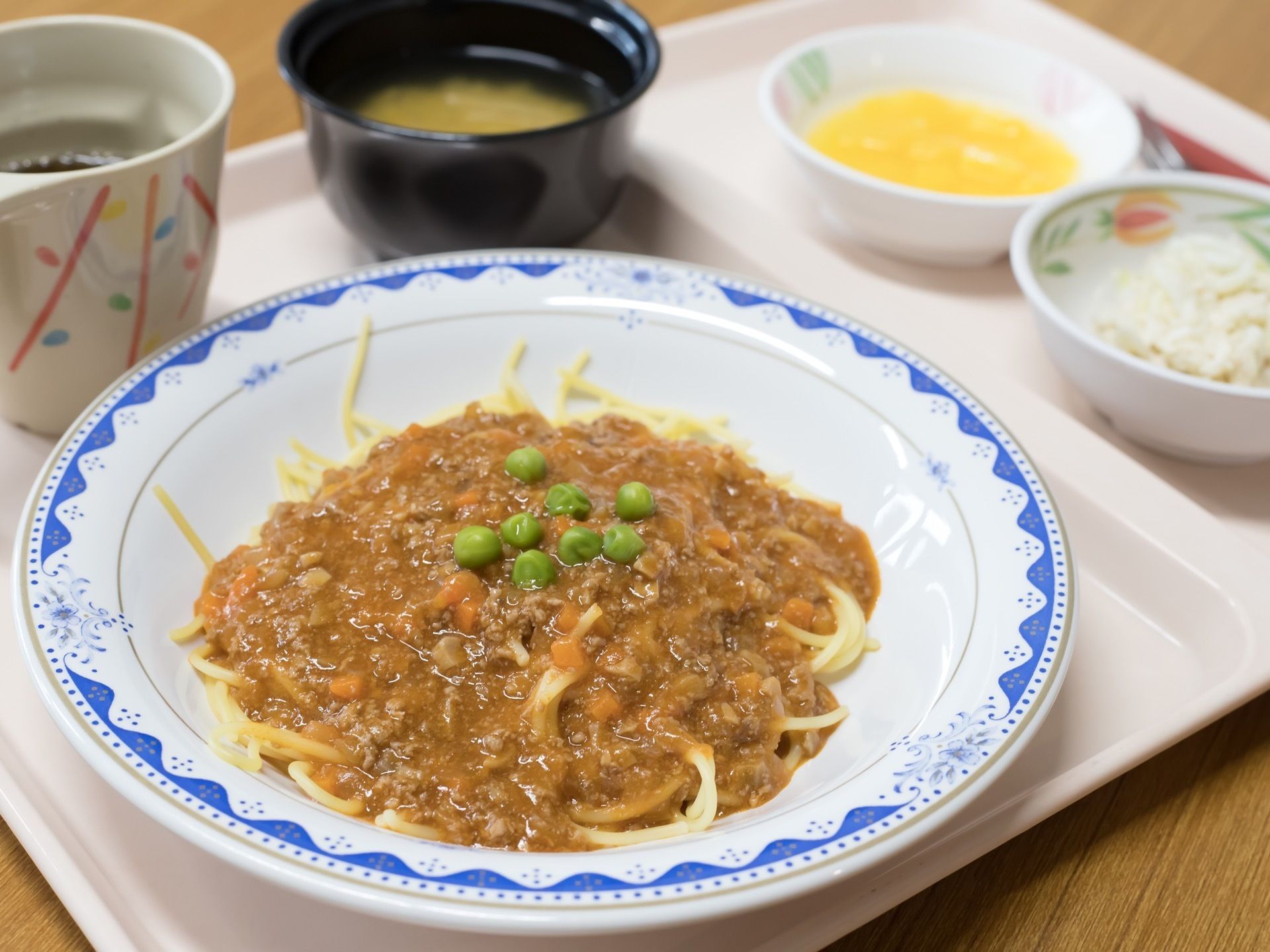二つに分かれたアイボリー色のトレーに、食事が載っている。メインはスパゲッティで、汁物やお茶、つけ合せもある。