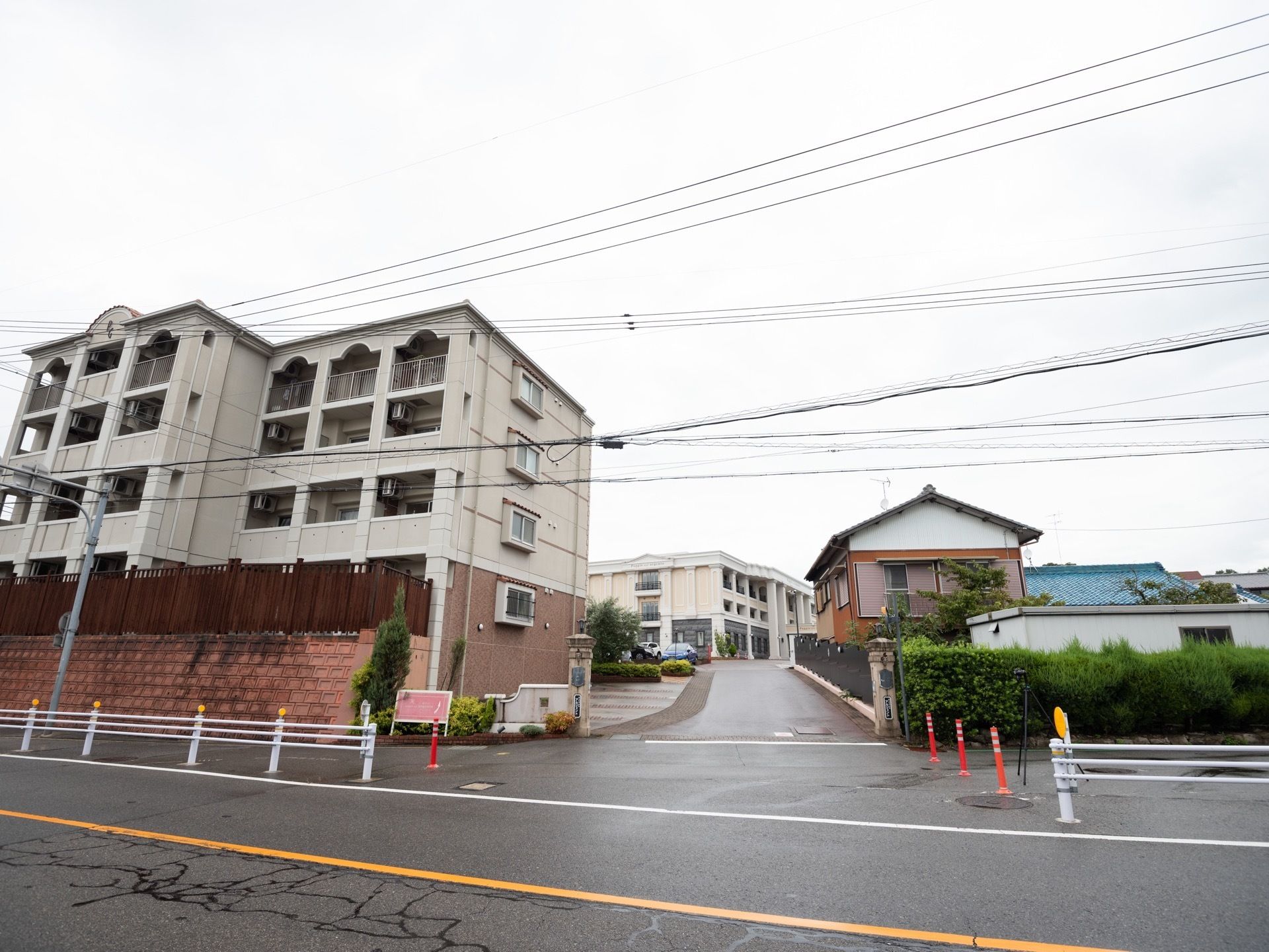 正面の坂を上がるとリゾートホテル風の３階建ての施設がある。同じ敷地内には、４階建ての賃貸マンションが建っている。
