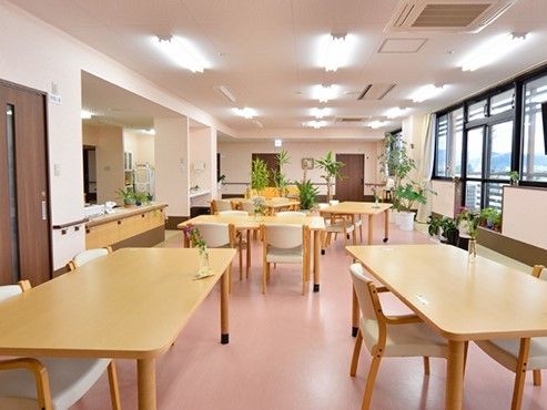 リビングスペースにいすや机が並んでいる写真。片方に採光性の高い窓