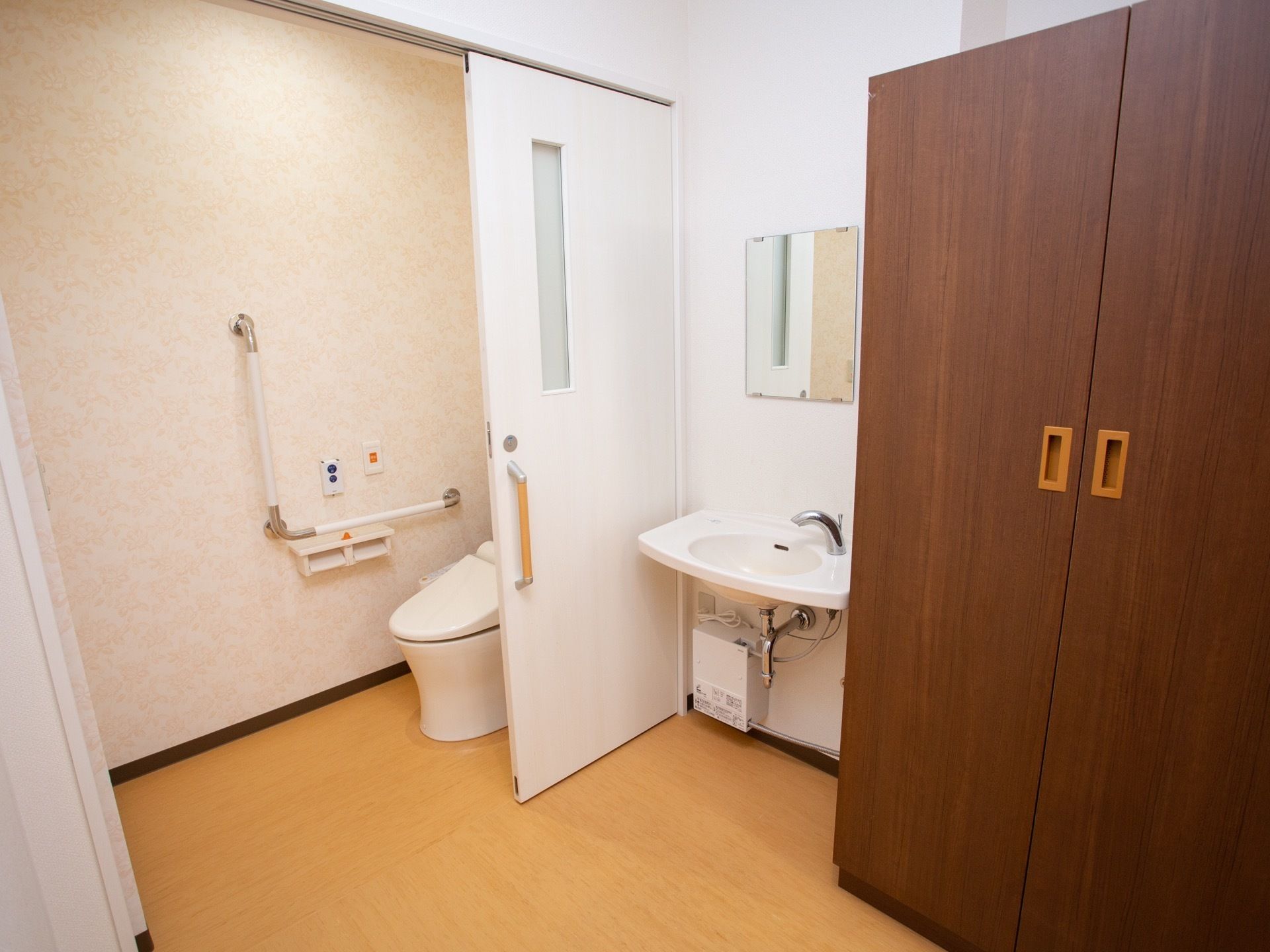 居室のトイレと洗面台の図である。右手前に大きな収納スペースがあり、その横に洗面台がある。奥に個室トイレがある。