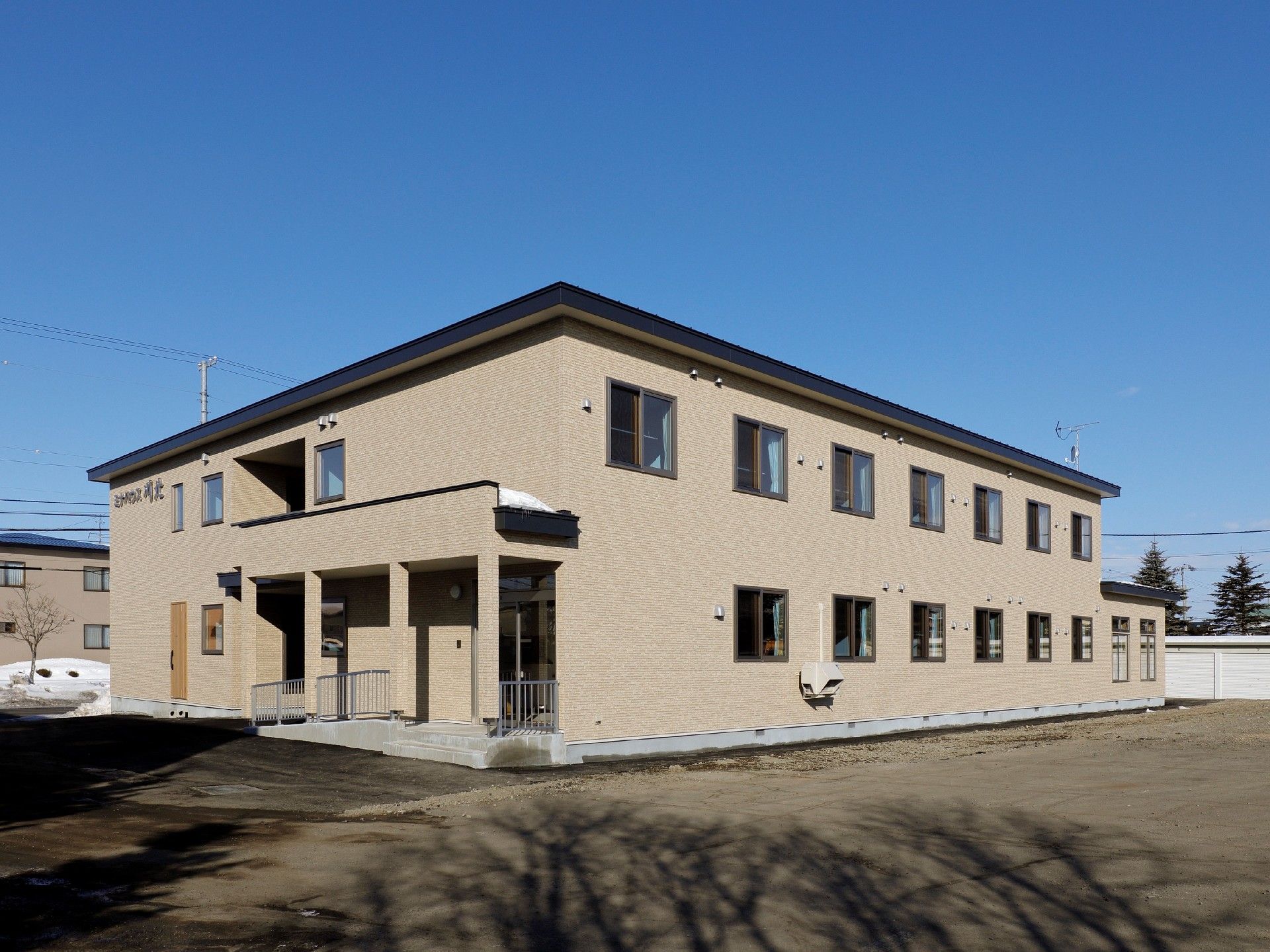 外観はすっきりとしたブラウン調の建物。２階建てでちょうど中央に玄関がある。