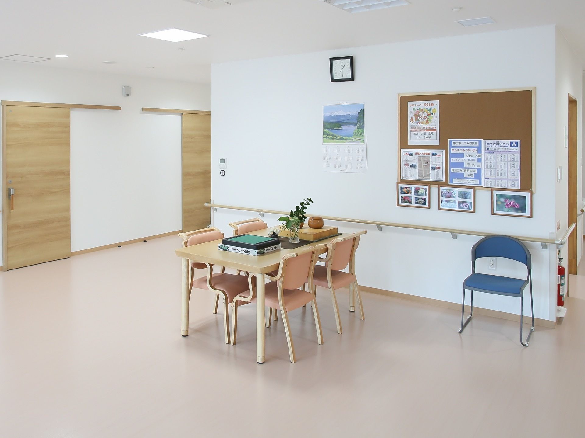 それぞれの階にはホールがあり、入居者様同士で囲碁や将棋を楽しむことができる。壁にはカレンダーや時計、写真や掲示物が飾られている。