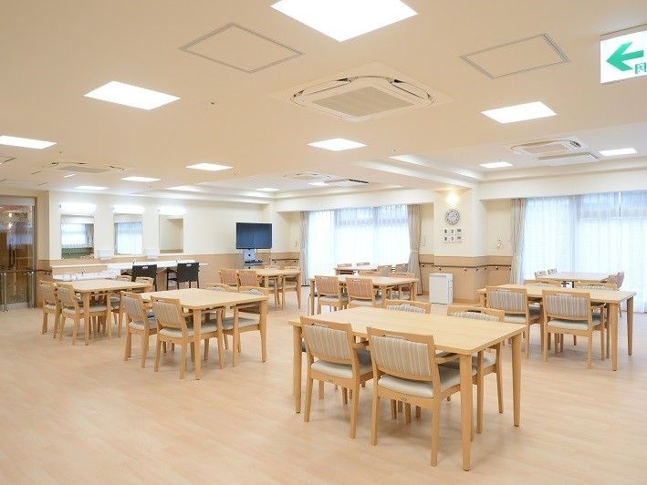 広い食堂はベージュの長テーブルが並び、各テーブルにはブラウンのいすが４脚ずつ置かれている。