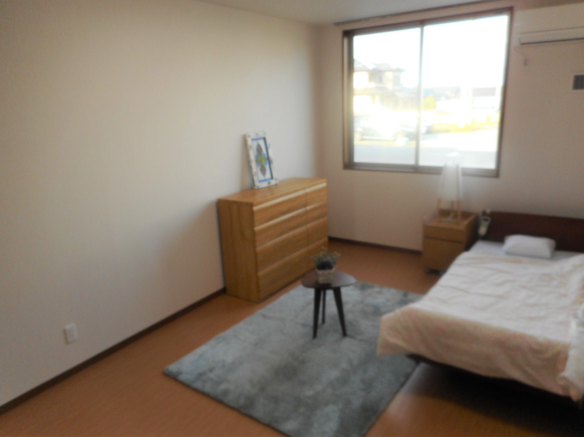 窓が大きく明るい雰囲気。ベッドやたんすなどの家具が設置された部屋は段差がなく快適。