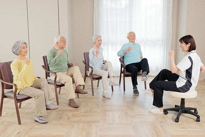 体の介助をするスタッフと高齢者。施設内の一室で介助している様子