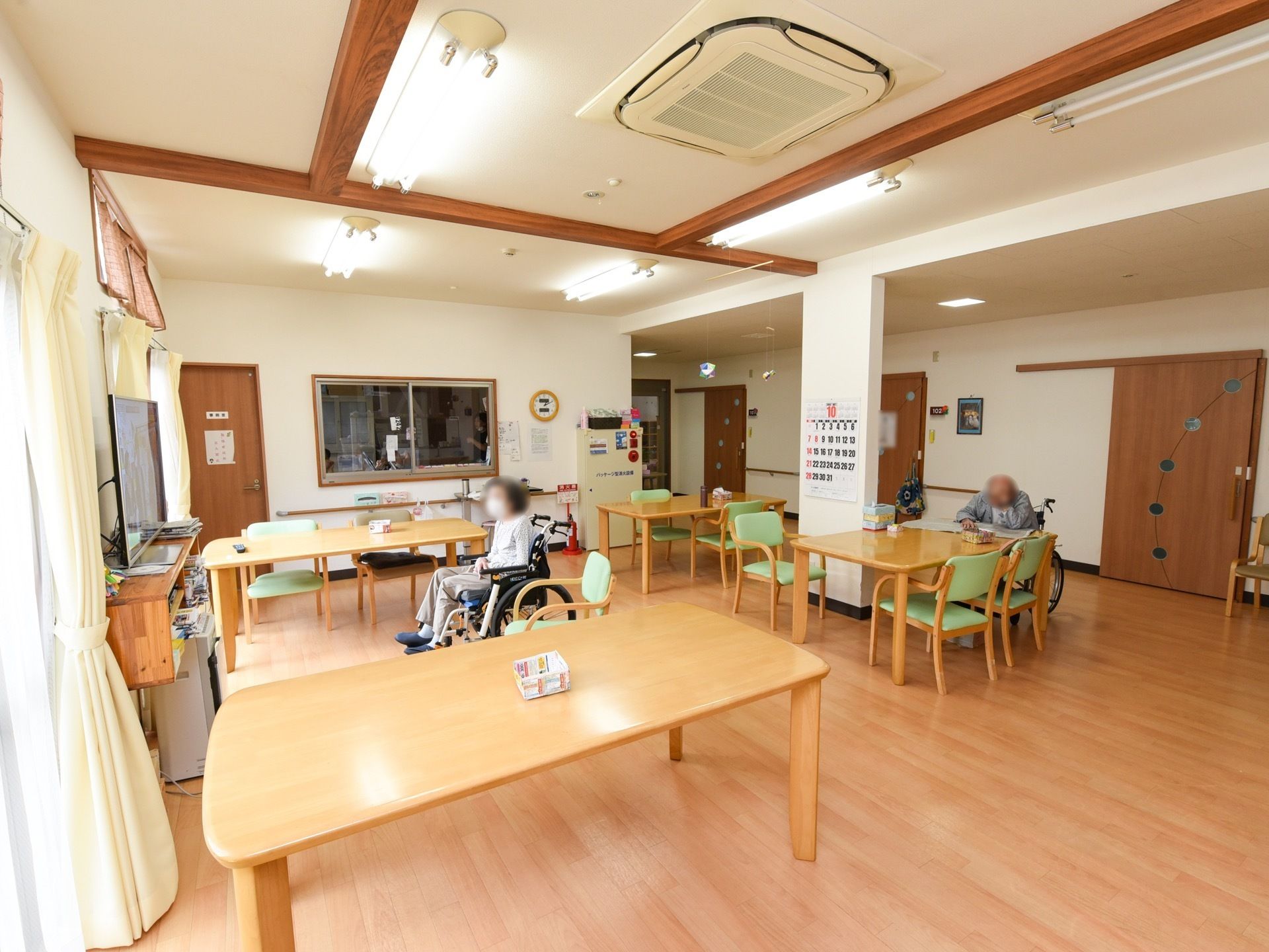 居室の並ぶ廊下へと続く一角が食堂になっている。柱が並び、扉がないので開放的である。すぐ隣には事務室の受付窓がある。