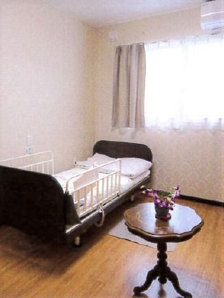 部屋の一角にベッドとテーブルが置いてある様子。窓から明かりが漏れているのが分かる