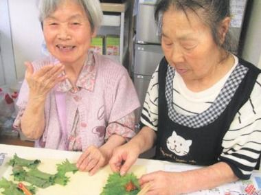 利用者2人が笑顔で料理している様子。リラックスしている表情