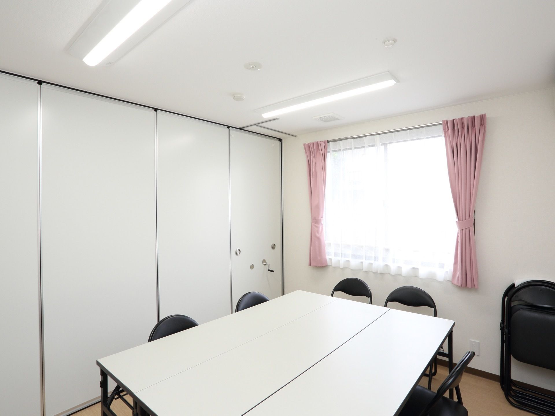 白を基調とした清潔感のある相談室である。フロア中央には、テーブルを囲んで黒いパイプ椅子が並べられている。