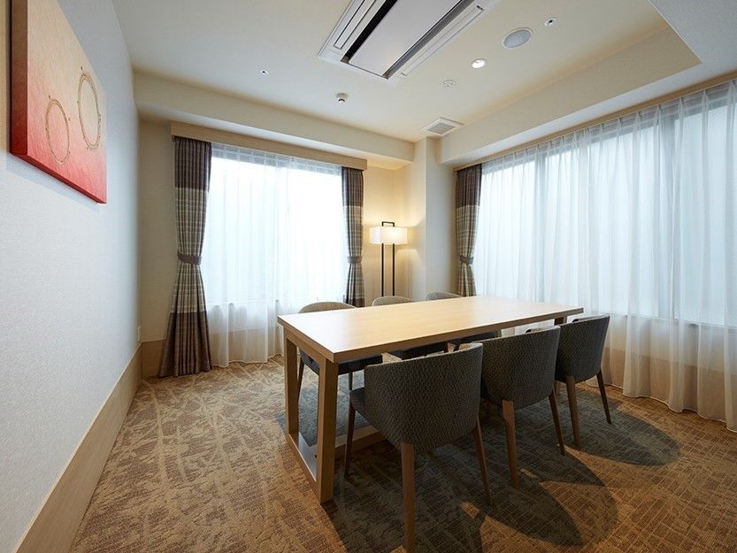 向かい合わせに３脚ずついすが並べられたテーブル。部屋は個室で左手にはモダンアートの作品が飾られている。