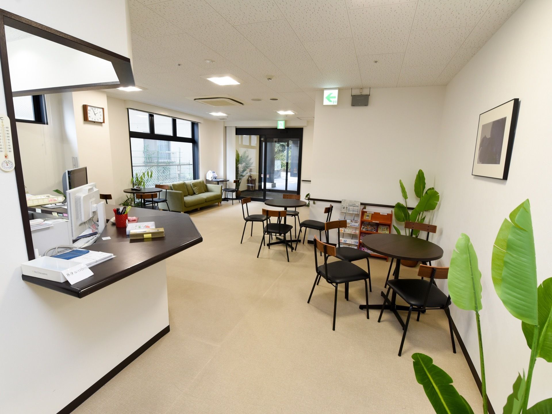 スタッフのカウンター脇にはソファやテーブル、椅子を置いたくつろぐことができるスペースがある。観葉植物が複数置かれている。