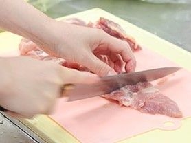 まな板の上で肉の筋を丁寧に取り除いている様子。
