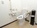 白を基調とした清潔感のあるトイレである。立ち上がりや座る際のサポートになる手すりやナースコールが設置されている。