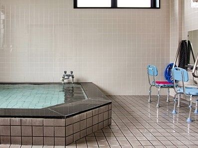 大浴場には大きな浴槽とシャワーが設置され、水色のシャワーチェアが二つある。