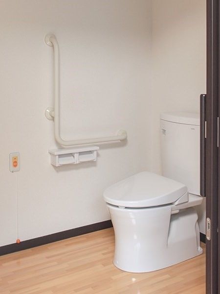 トイレには呼び出しボタンとエル字型の手すりを設置。居室との間に段差はなく、引き戸を採用。
