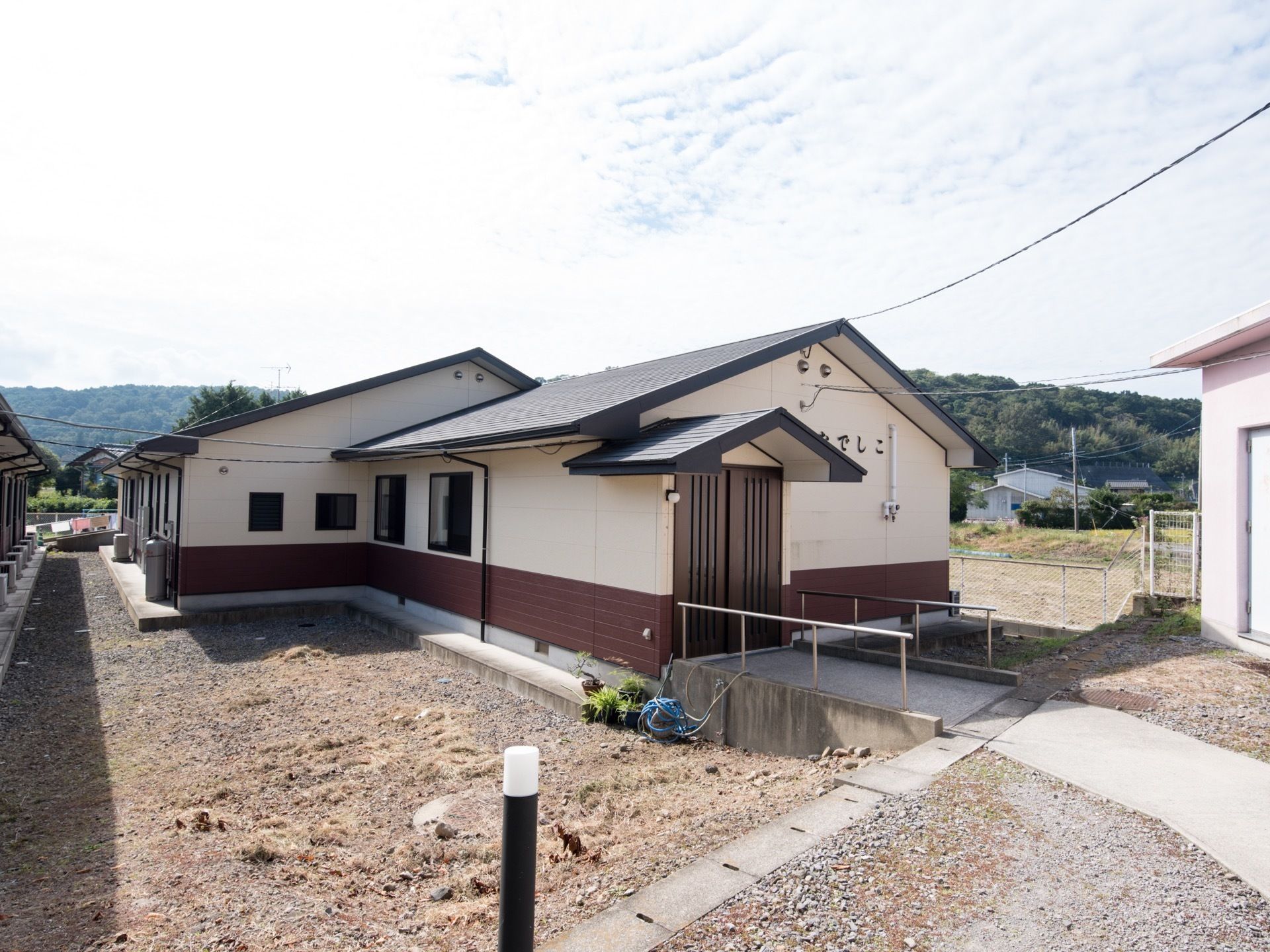 施設の外壁はベージュ色とダークブラウン色の２色になっており、平屋建ての建物である。玄関の扉はブラウンの引き戸になっている。