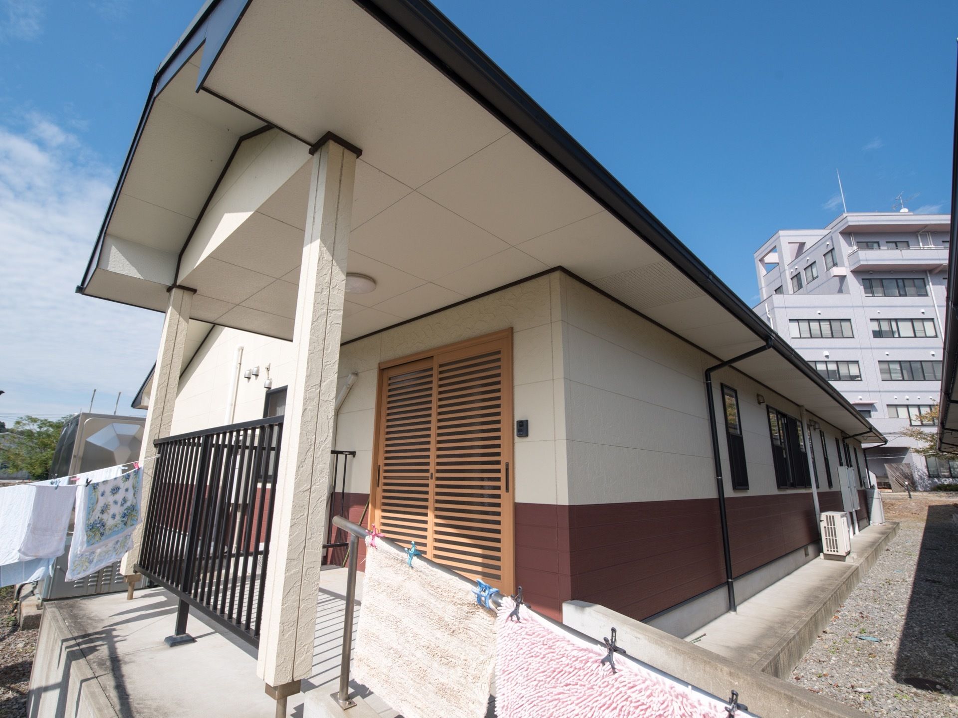施設の玄関前には大きな屋根のついたスペースがある。扉は引き戸になっており、その隣にインターホンが設置されている。
