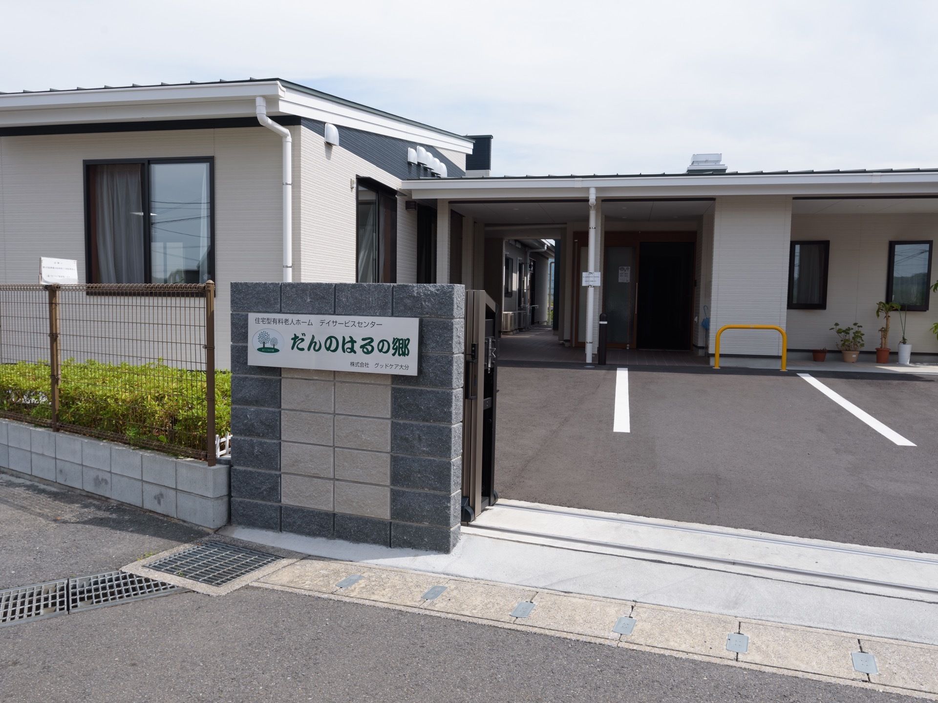 建物の前面はアスファルトで舗装され、駐車スペースが明示されている。石造り調の外壁に施設名表示看板が設置してある。