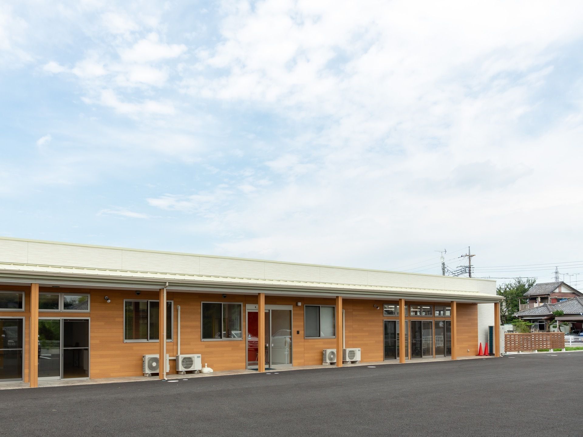 大きな窓があり、木のタイルで装飾された平屋建ての施設である。建物の周囲はコンクリートで舗装されている。