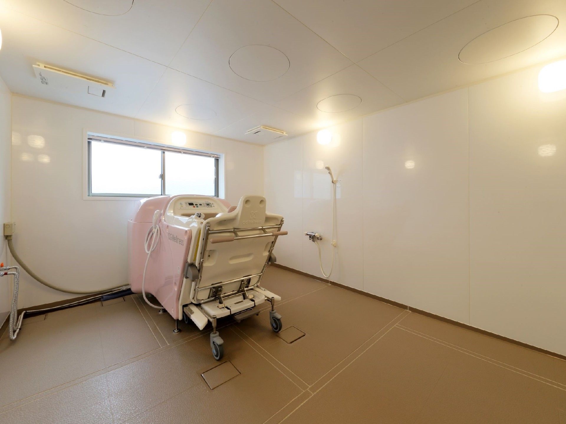 ピンクの機械浴槽が置かれた部屋は換気用の窓も大きく明るい雰囲気。シャワースペースもある。