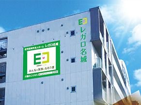 青い空の下に立つシャープな印象の建物。建物の側面にはホームの名前が書かれている。