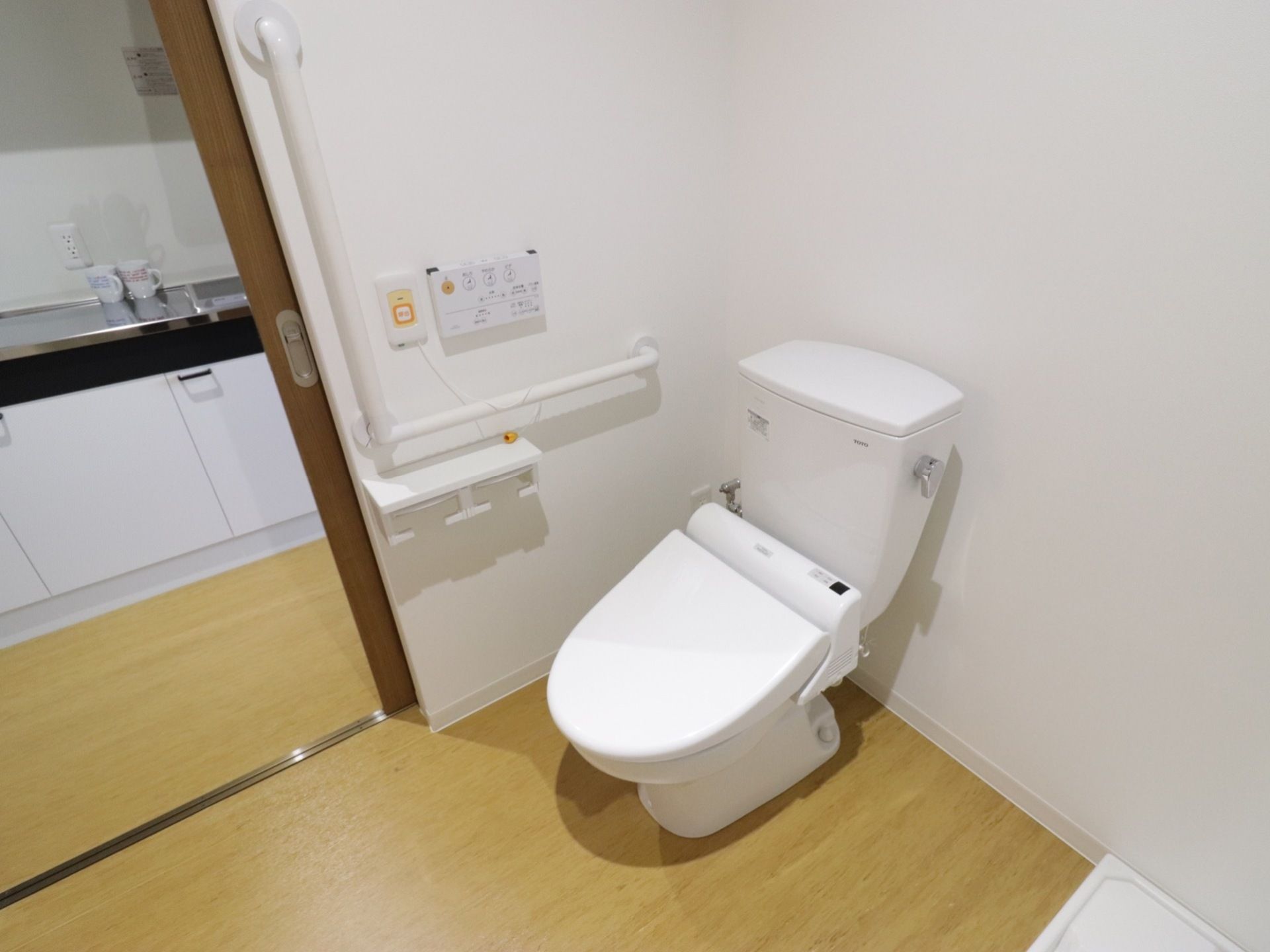 トイレ入口のドアは引き戸式である。洗浄機能付きの便器が設置され、便座脇にはＬ字型の手すりと非常呼び出しボタンが取りつけられている。