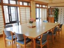 採光性の高い窓があるリビング。大きめのテーブルと椅子がある