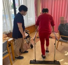 木陰を散歩する車椅子に乗った高齢女性と介助をする女性ヘルパー