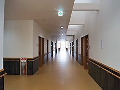 幅の広い廊下には手すりや消火器も設置されている。両サイドに居室を配置。