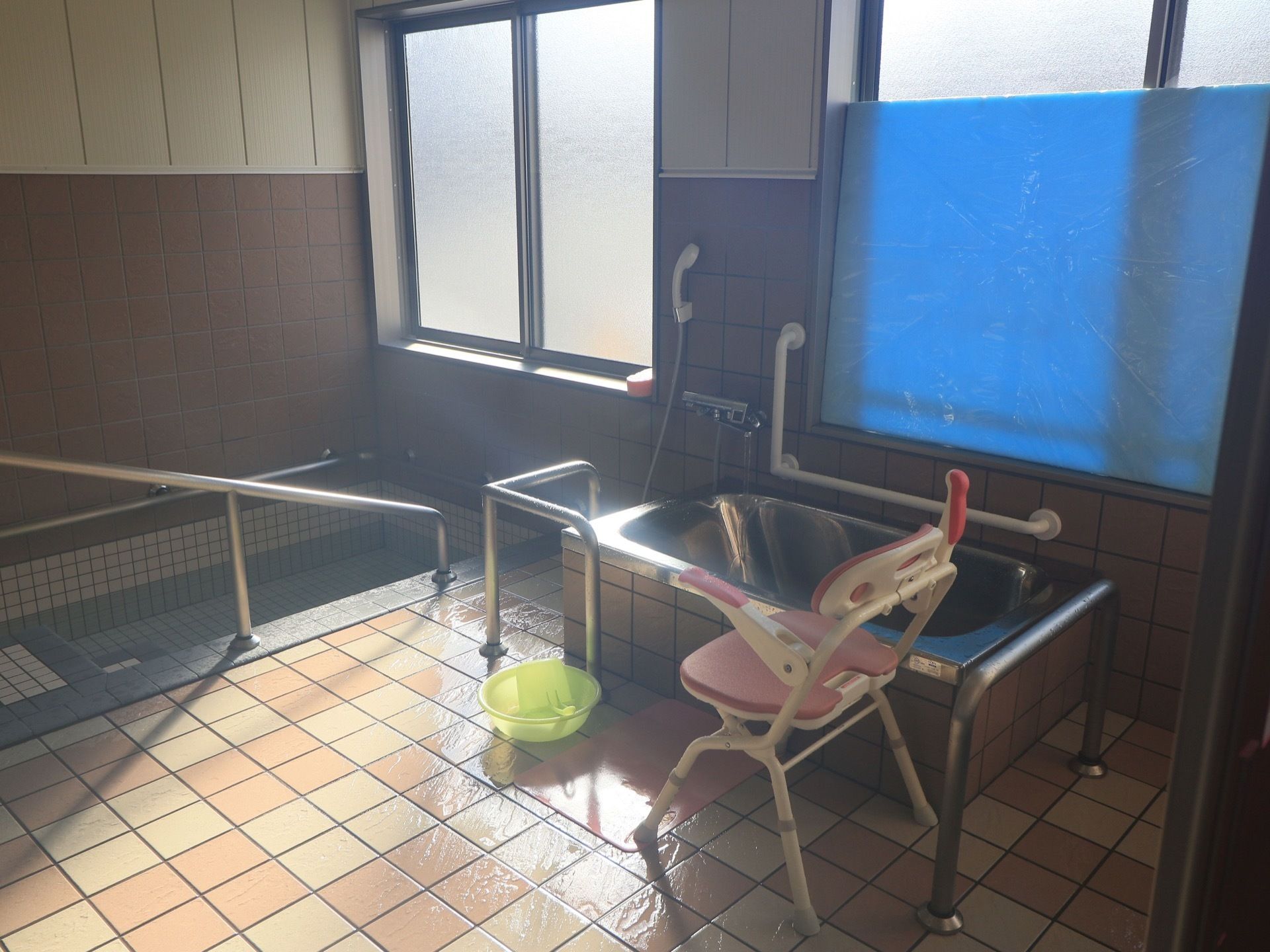 適度な光が入る浴室である。手すりを使って歩行しながら入浴できるバスタブと、個浴が楽しめるバスタブがある。バスチェアとバスマットもある。