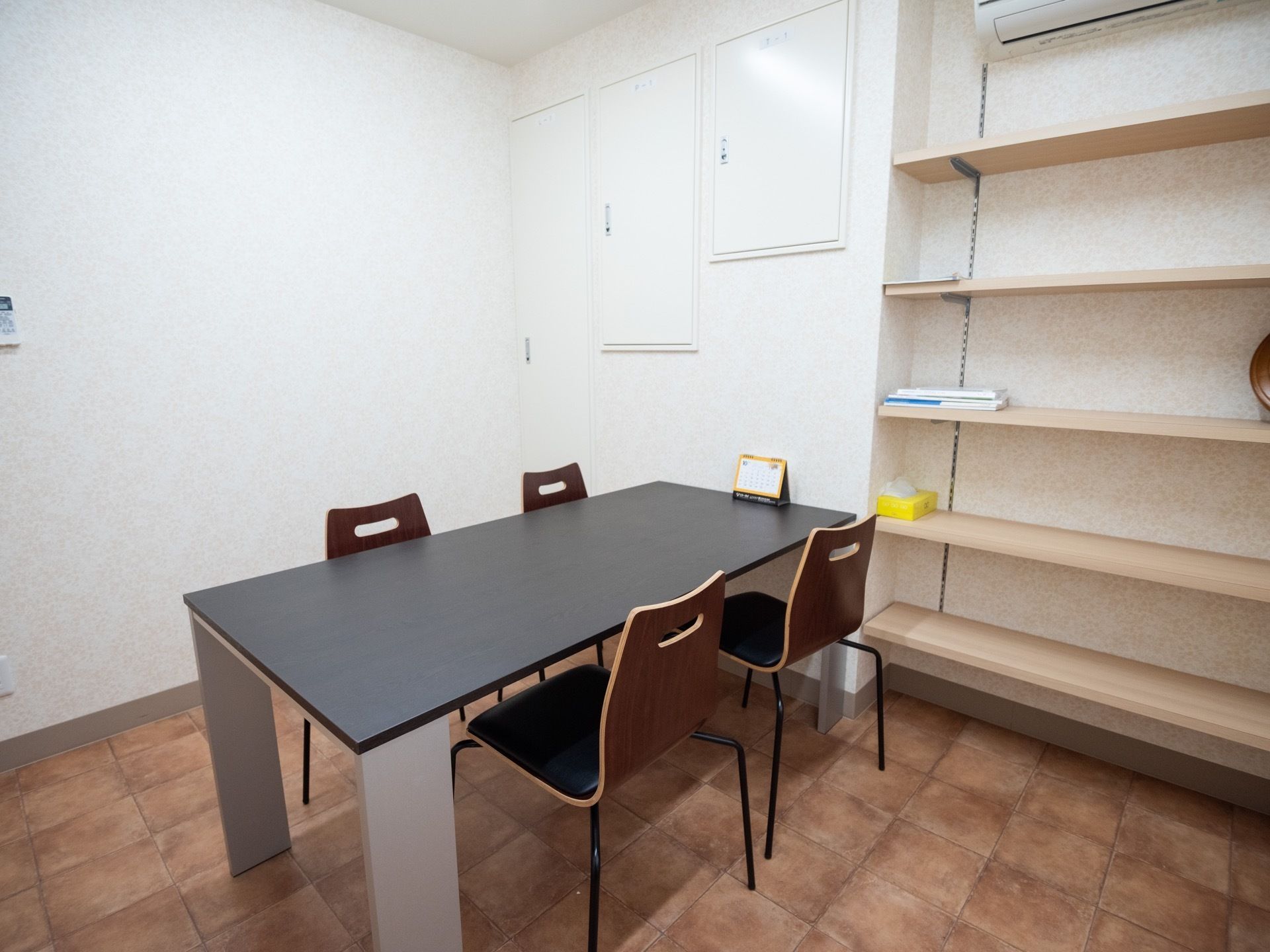 相談室にはテーブル一式と大きな棚が置かれている。壁には何も掛かっておらず、すっきりした室内になっている。