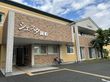 日当たりのいい木陰で話をしている高齢夫婦と若い女性。3人とも笑顔。