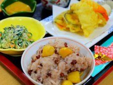 栗入りの赤飯と天ぷら、野菜の小鉢などが並んだトレイ。箸がきれいな袋に入れられている。