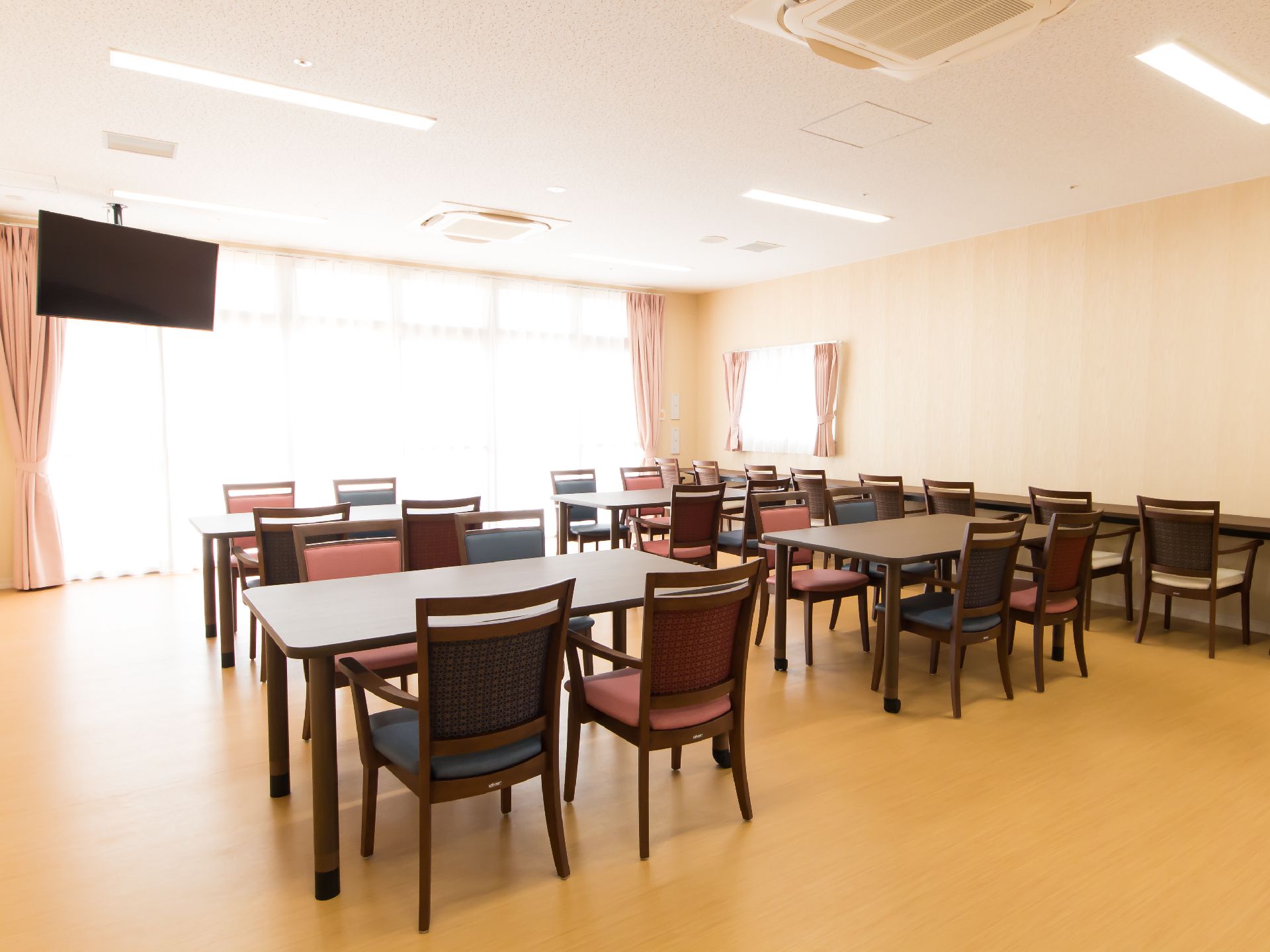 テーブルと椅子をゆったりと配置した、エアコンが天井にある共有スペース