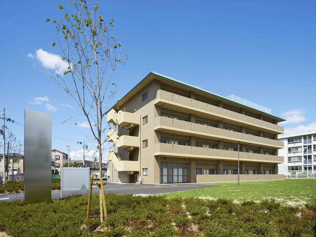 桜の花と花壇が手前にある建物の外観パース。ファミール・シャルレの外観。