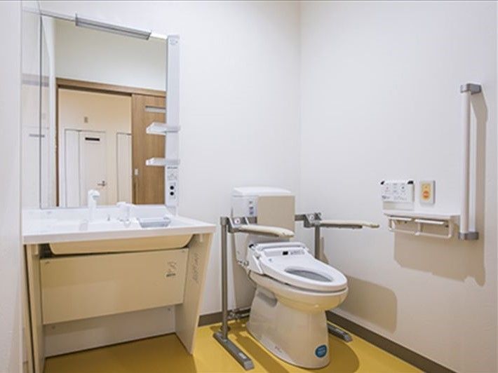 トイレには車いす対応の大きな洗面所もつき、背もたれや手すり、呼び出しボタンも設置され安全に使用できる。